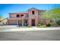 Two-story home featuring a three-car garage, stone accents, and a well-manicured front yard at 26703 N 90Th Dr, Peoria, AZ 85383