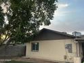 A view of the side of the house with a large shade tree and partial fence in the back yard at 3229 W Cholla St, Phoenix, AZ 85029