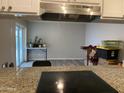 Kitchen view featuring a granite countertop, stainless range hood, and an opening to the living room at 3229 W Cholla St, Phoenix, AZ 85029