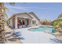 Gorgeous backyard featuring a sparkling pool, covered patio, and a lush tropical palm tree at 43319 W Oakland Ct, Maricopa, AZ 85138