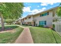Inviting townhome showcasing a well-manicured lawn, mature trees, and a charming walkway to the front door at 4599 N 17Th Ave, Phoenix, AZ 85015