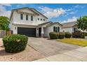 Inviting two-story home showcasing manicured bushes, a dark garage door, and a beautifully paved driveway at 512 E Bamboo Ln, San Tan Valley, AZ 85140