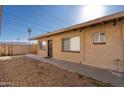 Side exterior view of the tan apartment building with a security door, multiple windows, and gravel at 7101 N 36Th Ave # 102, Phoenix, AZ 85051