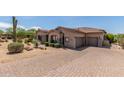 Attractive single-story house featuring a paver driveway, three-car garage and low maintenance desert landscaping at 8725 E Menlo Cir, Mesa, AZ 85207