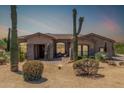 Inviting single-story home featuring desert landscaping, including saguaro cacti, and a charming front porch at 8725 E Menlo Cir, Mesa, AZ 85207