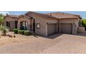 Attractive single-story house featuring a paver driveway, three-car garage and low maintenance desert landscaping at 8725 E Menlo Cir, Mesa, AZ 85207