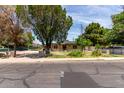 View of the home from across the street with lawn and mature trees in front and off-street parking in back at 1134 W 2Nd St, Mesa, AZ 85201