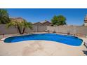 Sparkling blue pool surrounded by a patio and block wall for privacy at 12422 W Rosewood Dr, El Mirage, AZ 85335