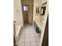 Well-lit bathroom featuring a bathtub, a single sink vanity with drawers, and a white tile floor at 13241 W Desert Ln, Surprise, AZ 85374