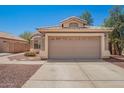 Exterior shot of a tan single-story home with a two-car garage and low-maintenance desert landscaping at 13241 W Desert Ln, Surprise, AZ 85374