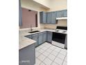Cozy kitchen featuring sleek countertops, blue cabinets, white tile floor, and modern appliances at 13241 W Desert Ln, Surprise, AZ 85374