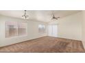 Bright living room with neutral carpet, multiple windows, and a contemporary ceiling fan at 1608 S 82Nd Dr, Phoenix, AZ 85043