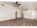Spacious living room with neutral carpet and ceiling fan, showcasing a clean and open layout at 1608 S 82Nd Dr, Phoenix, AZ 85043