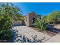 Attached two-car garage showcasing a wide driveway and mature landscaping under a clear blue sky at 20557 W Lost Creek Dr, Buckeye, AZ 85396