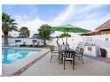 Backyard pool area with lounge chairs, dining table, built in BBQ, and green umbrella at 3224 E Desert Cove Ave, Phoenix, AZ 85028