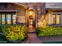 Inviting front exterior of home showcasing a stone facade and archway, complemented by vibrant yellow flowers and lush greenery at 3460 E Lynx Pl, Chandler, AZ 85249
