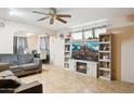 Spacious living room featuring a ceiling fan, tile flooring, and built-in entertainment center with fireplace at 8724 N 28Th Ave, Phoenix, AZ 85051