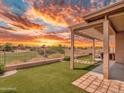 A spacious backyard features manicured synthetic grass, a covered patio, and views of the golf course at 11547 W King Snake Ct, Surprise, AZ 85378
