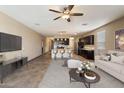 Open-concept living room boasts modern decor, ceiling fan, and seamless flow to the kitchen at 13612 W Desert Moon Way, Peoria, AZ 85383