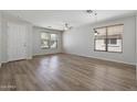 Bright living room with wood-look floors, ceiling fan, and multiple windows providing natural light at 18391 W Stinson Dr, Surprise, AZ 85374