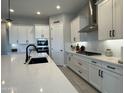 Modern kitchen with white cabinets, black hardware, stainless steel appliances, and a large island at 25602 S 229Th Pl, Queen Creek, AZ 85142