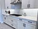 Updated kitchen with white cabinets, subway tile backsplash, black hardware, and stainless steel hood at 25602 S 229Th Pl, Queen Creek, AZ 85142