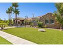 A luxurious property showcasing a beautifully landscaped front lawn, elegant stone accents, and a covered entrance at 3731 E Halifax Cir, Mesa, AZ 85205