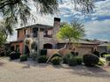 Beautiful exterior of a two-story home with stone accents, a balcony and a landscaped yard at 7751 E Golden Eagle Cir, Gold Canyon, AZ 85118