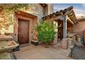 Charming entryway with stone columns, a wooden door, covered seating area and decorative water fountain at 7751 E Golden Eagle Cir, Gold Canyon, AZ 85118