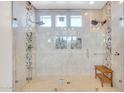 Bright glass shower featuring tiled walls, built-in shelving, shower bench, and dual shower heads at 10613 E Knowles Ave, Mesa, AZ 85209