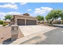 A house featuring a spacious concrete driveway leading to a three-car garage, framed by desert landscaping at 15989 W Indianola Ave, Goodyear, AZ 85395