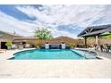 Beautiful pool with a waterfall feature and a covered seating area, perfect for outdoor relaxation at 17815 W Straight Arrow Ln, Surprise, AZ 85387
