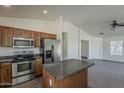 Open kitchen with stainless steel appliances, center island, and ample cabinet space, perfect for cooking and entertaining at 20761 N Herbert Ave, Maricopa, AZ 85138