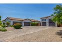 Spacious driveway providing ample parking and access to the multiple garages, surrounded by desert landscaping at 24372 N 96Th Ln, Peoria, AZ 85383