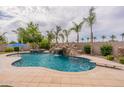 Beautiful pool with a rock waterfall feature, diving board, and mature palm trees in a private backyard at 550 W Powell Way, Chandler, AZ 85248