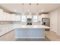 A gourmet kitchen with white cabinets, a large island, stainless steel appliances, and modern backsplash at 613 W Winchester Dr, Chandler, AZ 85286