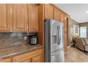 Kitchen featuring granite countertops, stainless steel refrigerator, and warm wood cabinets at 6840 S Crystal Way, Chandler, AZ 85249