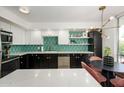 Modern kitchen boasts black and white cabinetry, stylish backsplash, stainless steel appliances, and a round dining table at 1225 E Medlock Dr # 206, Phoenix, AZ 85014
