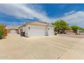 View of the home's 3-car garage and low maintenance landscaping with desert shrubs at 13368 W Rimrock St, Surprise, AZ 85374