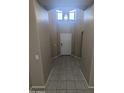 Bright hallway with neutral colors, tiled floors, transom windows, and an attractive light fixture at 14841 W Desert Hills Dr, Surprise, AZ 85379