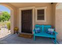 Welcoming front porch with a cheerful blue bench, decorative pillows, and a 'Welcome' mat, creating a warm entrance at 18542 W Valerie Dr, Surprise, AZ 85374