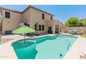 Backyard oasis with a sparkling pool, green umbrella, and comfortable lounge seating, ideal for relaxation and entertaining at 18542 W Valerie Dr, Surprise, AZ 85374