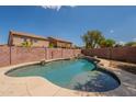 Beautiful backyard pool with rock accents and mature landscaping surrounded by brick fence at 33055 N Madison Way Dr, San Tan Valley, AZ 85144