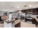 Open kitchen with stainless steel appliances, dark cabinetry, granite countertops, and tile flooring at 40345 W Molly Ln, Maricopa, AZ 85138