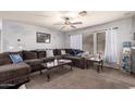 Cozy living room featuring a large, comfortable sectional sofa, ceiling fan and natural light from the windows at 40345 W Molly Ln, Maricopa, AZ 85138
