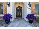 Elegant front entrance featuring iron double doors, stone archway, potted flowers, and tiled walkway at 7482 S Mccormick Way, Queen Creek, AZ 85142