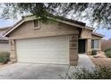 Home featuring an attached two-car garage, desert landscaping, and a covered entryway at 7771 N 58Th Ln, Glendale, AZ 85301