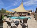 Backyard pool features desert landscaping, shade sails, and ample lounge seating at 9983 W Monterosa Ave, Phoenix, AZ 85037