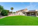 Expansive backyard featuring artificial turf, a covered patio, and solar panels on the home's roof at 1203 W Escuda Rd, Phoenix, AZ 85027