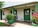 Inviting front porch with green door, potted flowers, and seating area for relaxing outdoors at 2916 N 48Th Ave, Phoenix, AZ 85031
